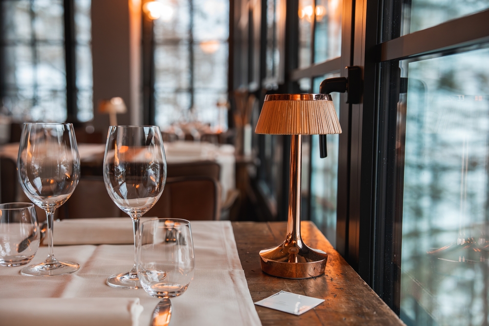 Table dressée avec verres à vin près des baies vitrées, restaurant partenaire de L'Annexe à Gérardmer