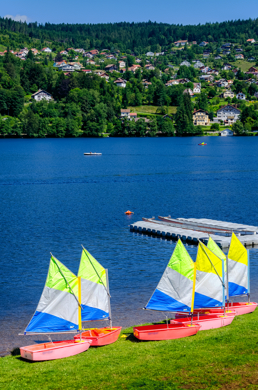 Petits voiliers colorés sur le lac de Gérardmer, activités nautiques près de l'hôtel