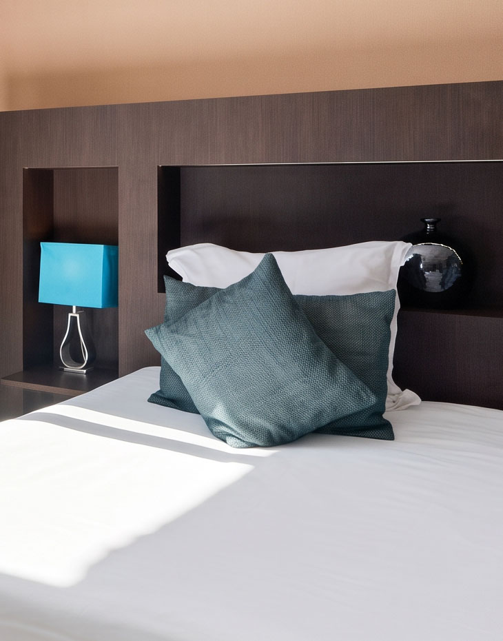 Lit avec coussins bleu canard et lampe de chevet, chambre deluxe de l'hôtel La Réserve Gérardmer