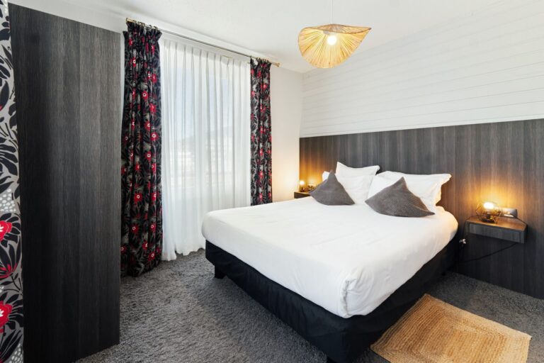 Chambre supérieure lumineuse, lit double et tête de lit en bois sombre, hôtel à Gérardmer