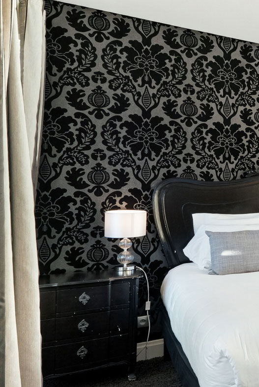 Table de chevet et lampe sur papier peint baroque, chambre deluxe de l'hôtel La Réserve Gérardmer