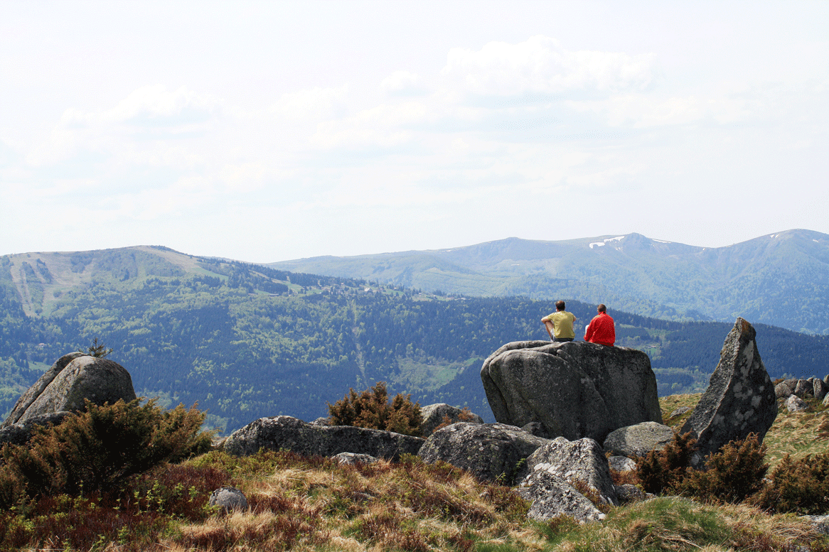Randonneurs sur des rochers face aux sommets du massif des Vosges