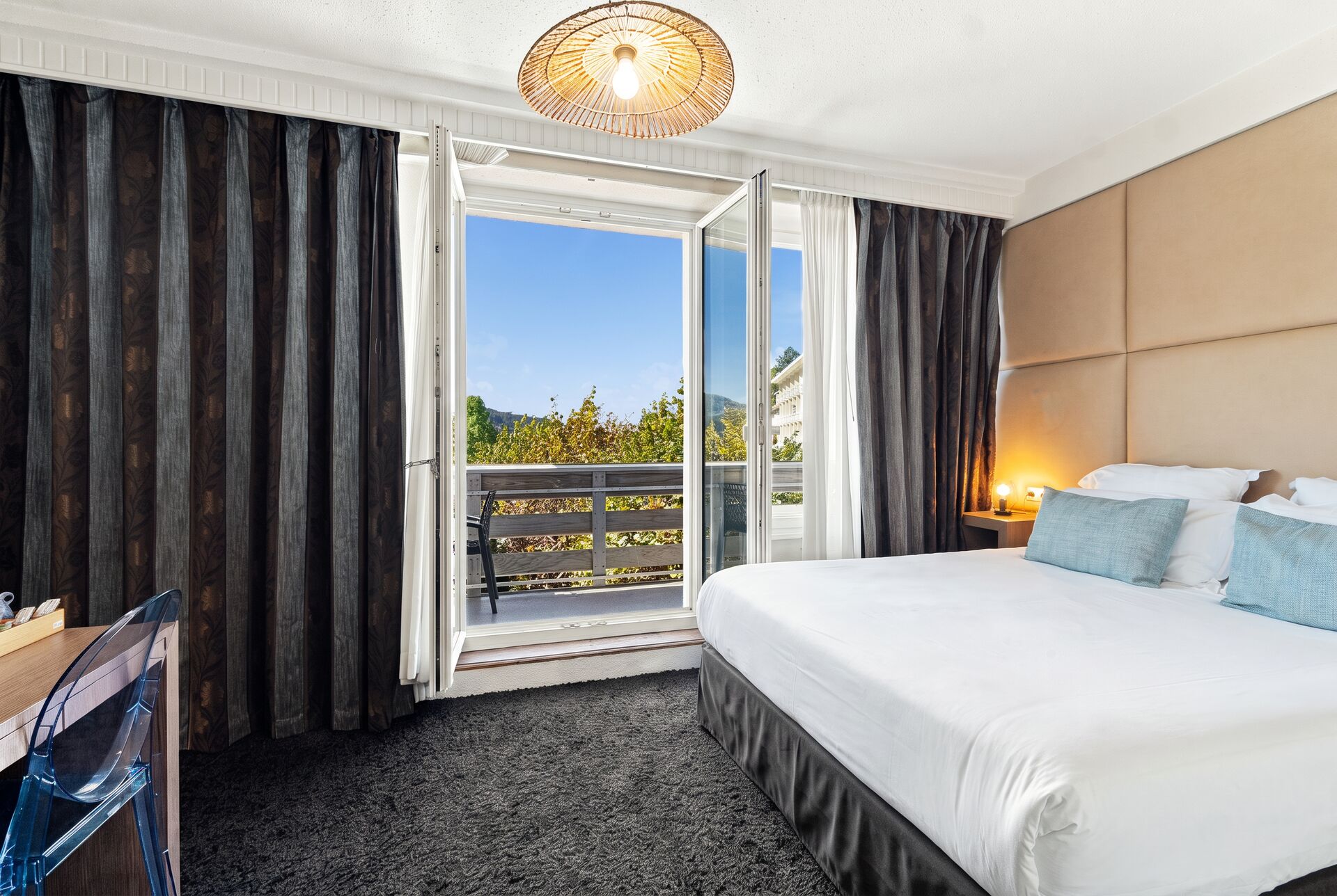 Chambre deluxe vue lac avec balcon, porte-fenêtre ouverte et grand lit, hôtel à Gérardmer